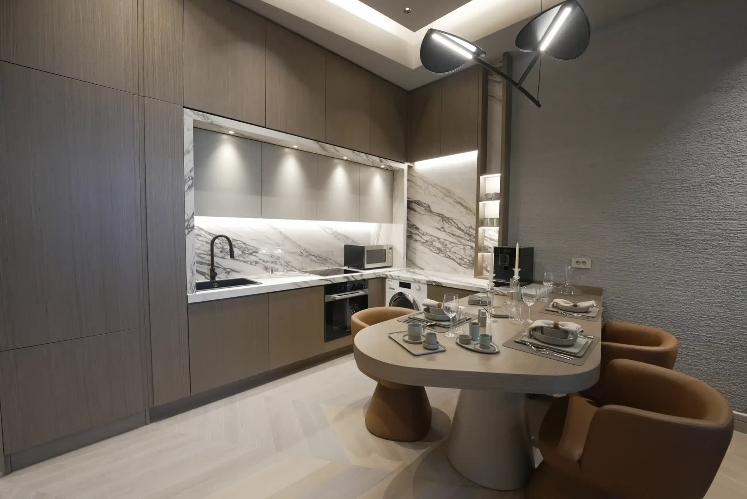 Kitchen with a marble splashback and integrated appliances, beside a round dining table set for four