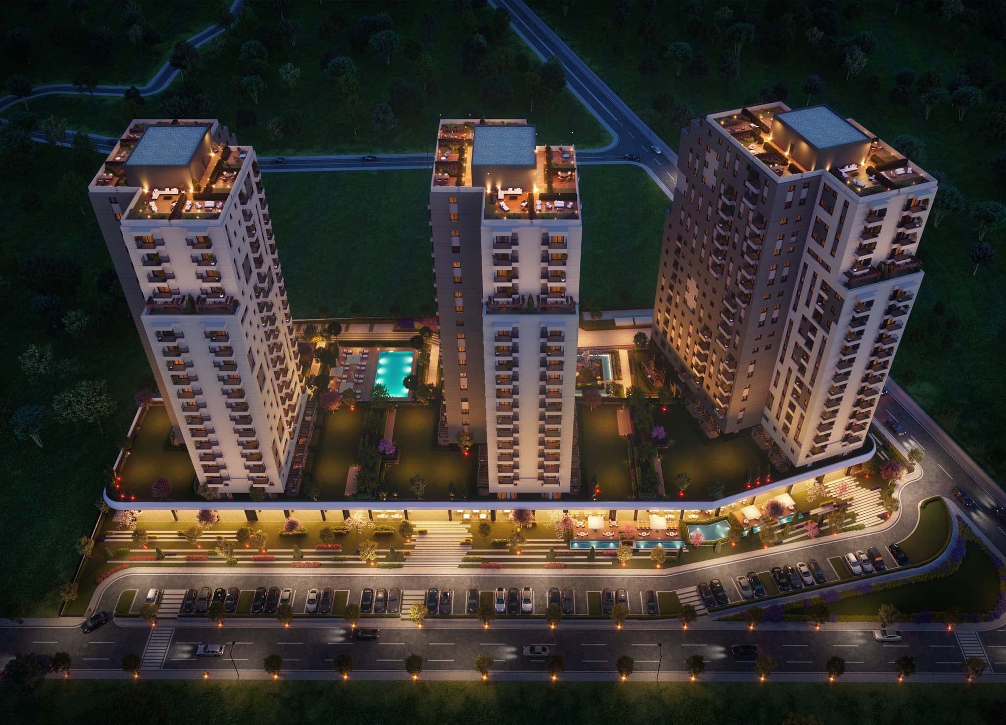 Night-time aerial view of the whole AS Concept site, with three towers around a lit courtyard swimming pool, landscaped gardens and a parking row along the road — artist's impression