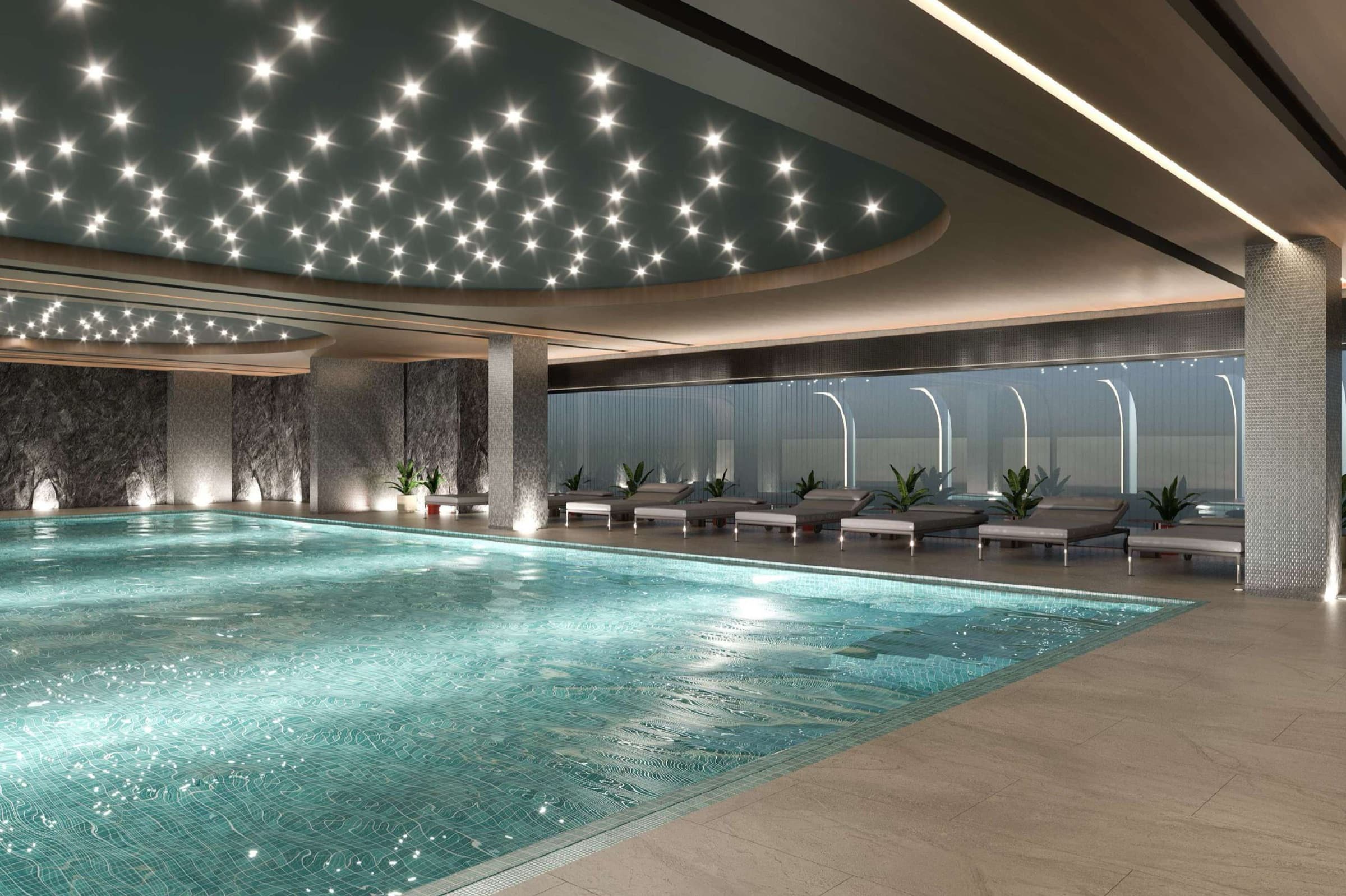 The indoor swimming pool at Boğaz Çamlıca under a fibre-optic star ceiling, stone-clad columns and loungers running the length of the poolside