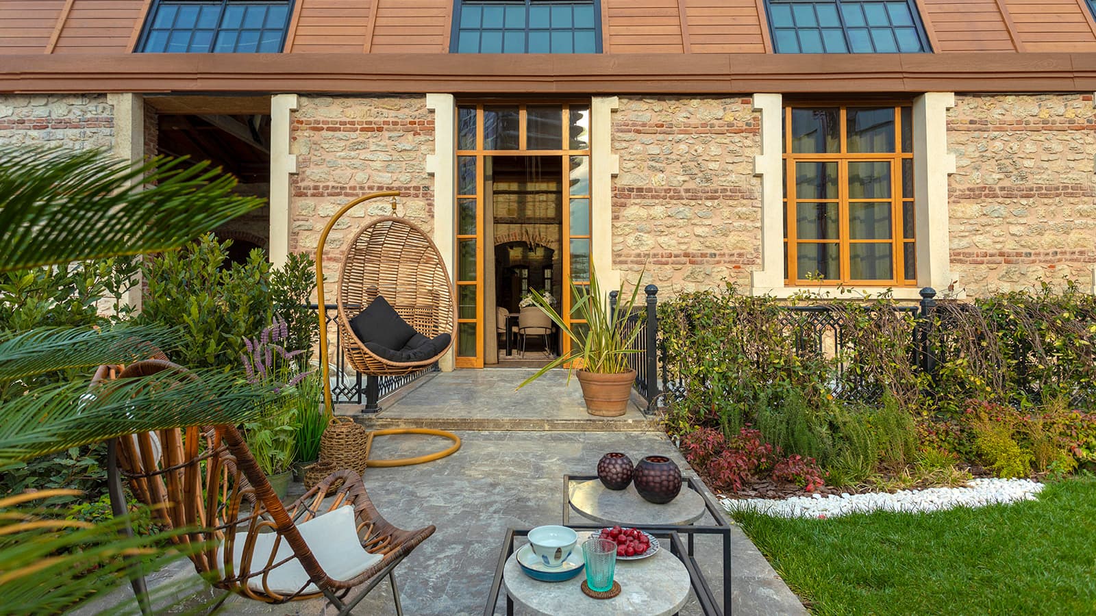 Restored stone and timber facade of the heritage building with a garden terrace and hanging rattan chair