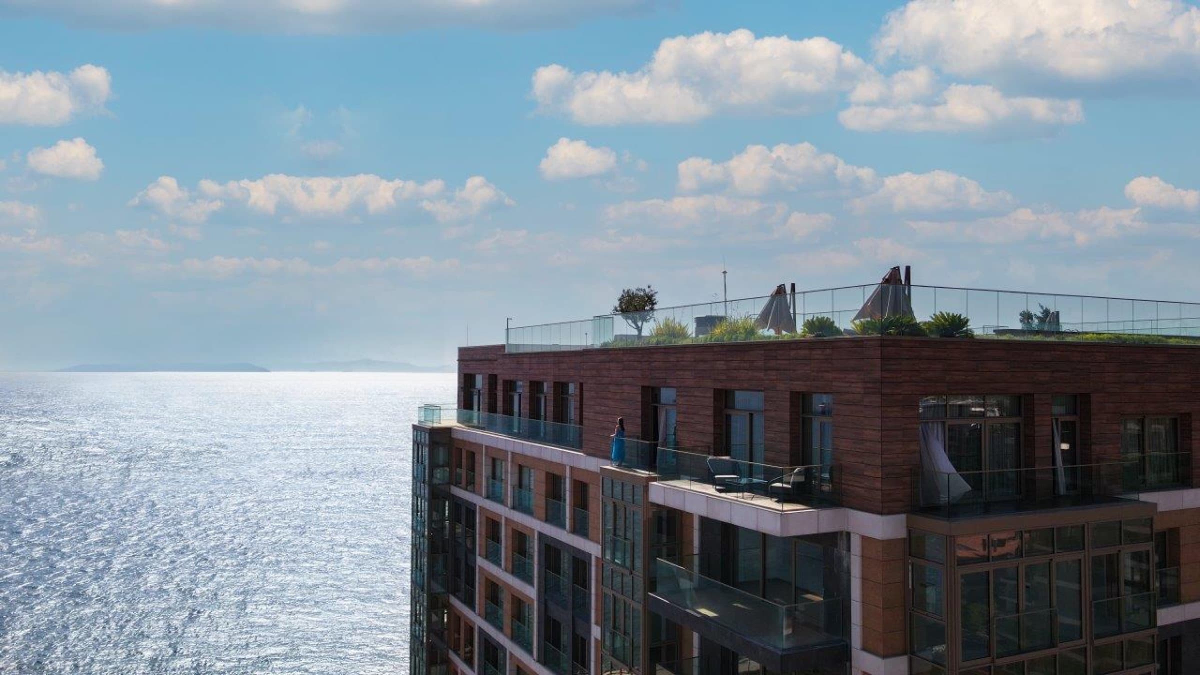 Seafront tower meeting the water, its rooftop garden planted above the top floor