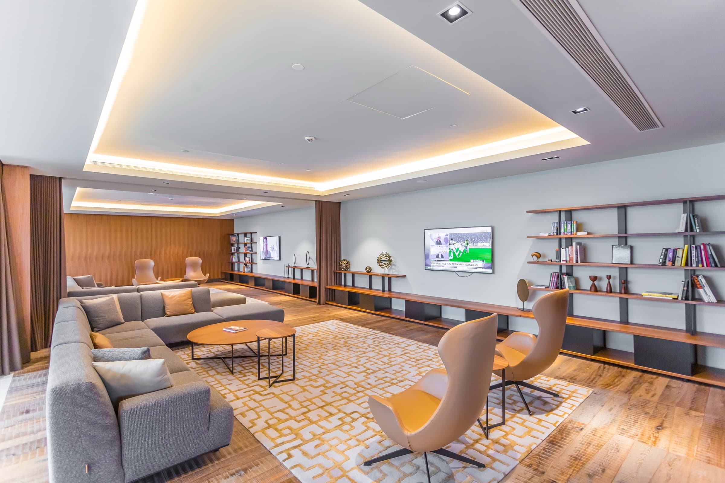 Residents' lounge and library at Emaar Square İstanbul, walnut shelving running the length of the wall