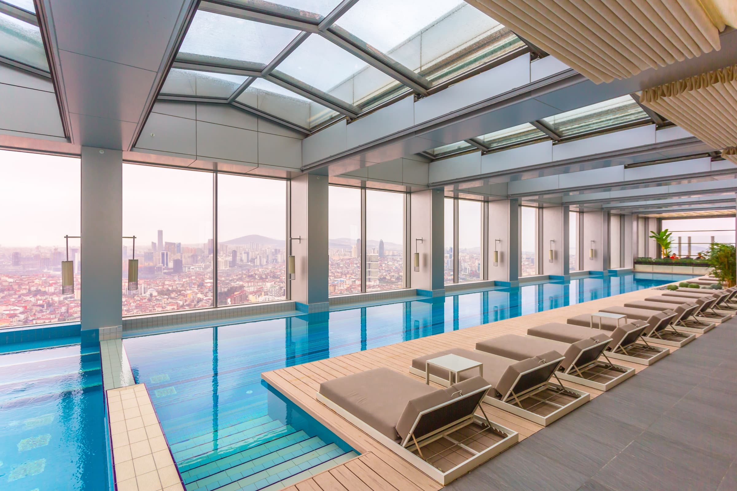The top-floor indoor pool at Emaar Square İstanbul under its glazed roof, looking out over Istanbul