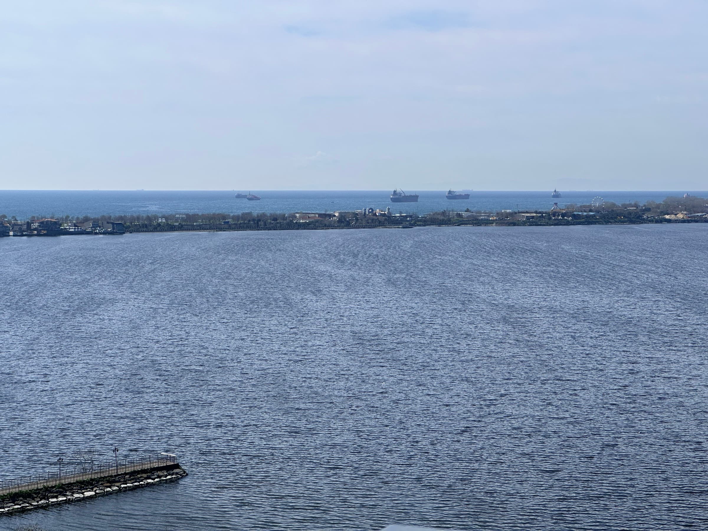 Looking south-west from Kırımlı Park across Küçükçekmece Lake to the narrow shore strip that divides it from the Marmara Sea, cargo ships at anchor offshore