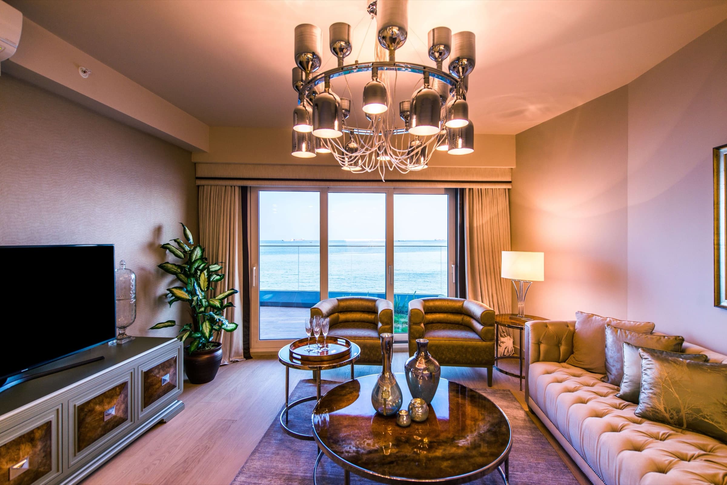 The living room of a sea-facing residence at SeaPearl Ataköy, a sliding glazed wall opening onto the terrace with the Marmara filling the opening