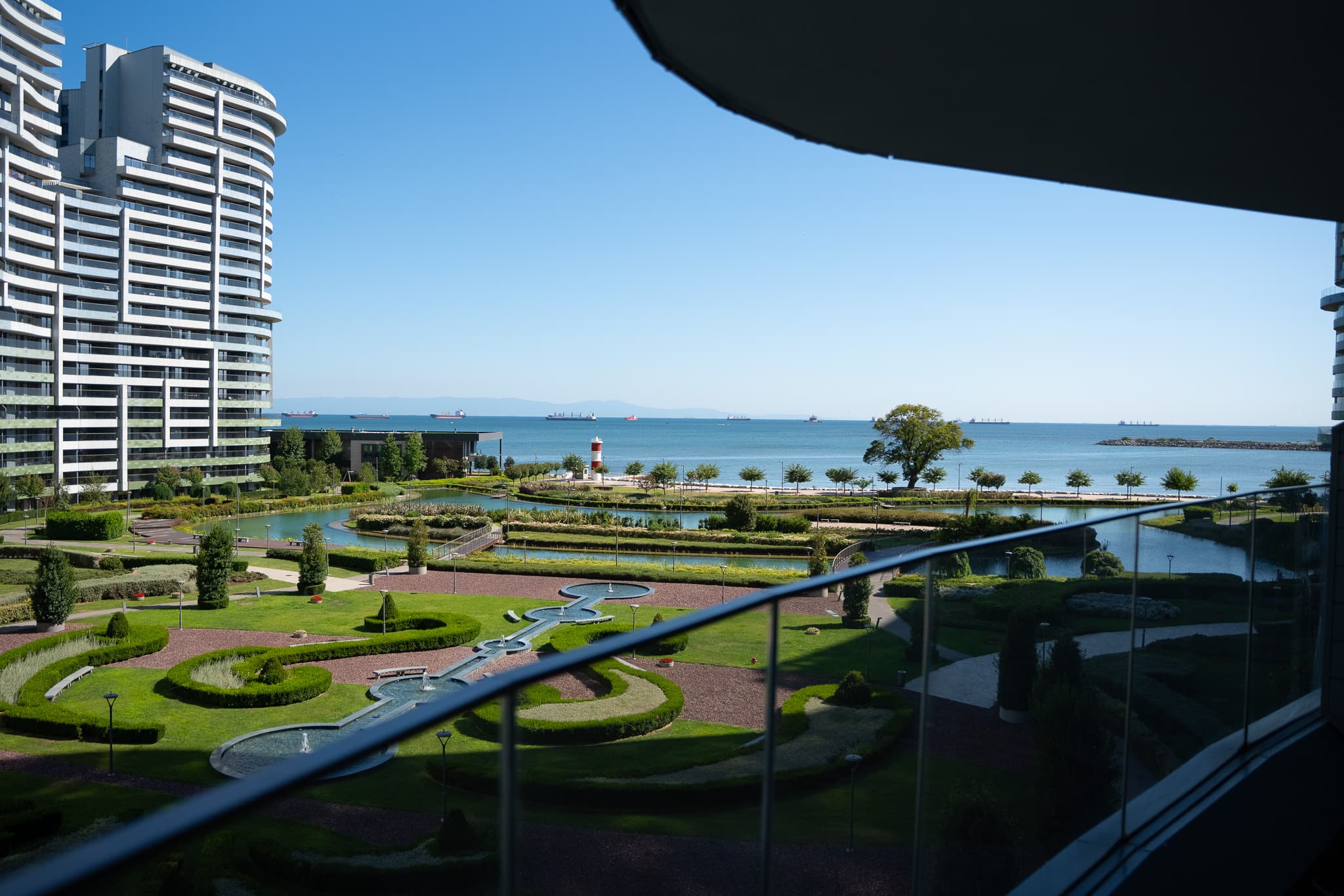 The view from a balcony at SeaPearl Ataköy over the project's formal gardens and pools to the Marmara Sea, with cargo ships at anchor along the horizon