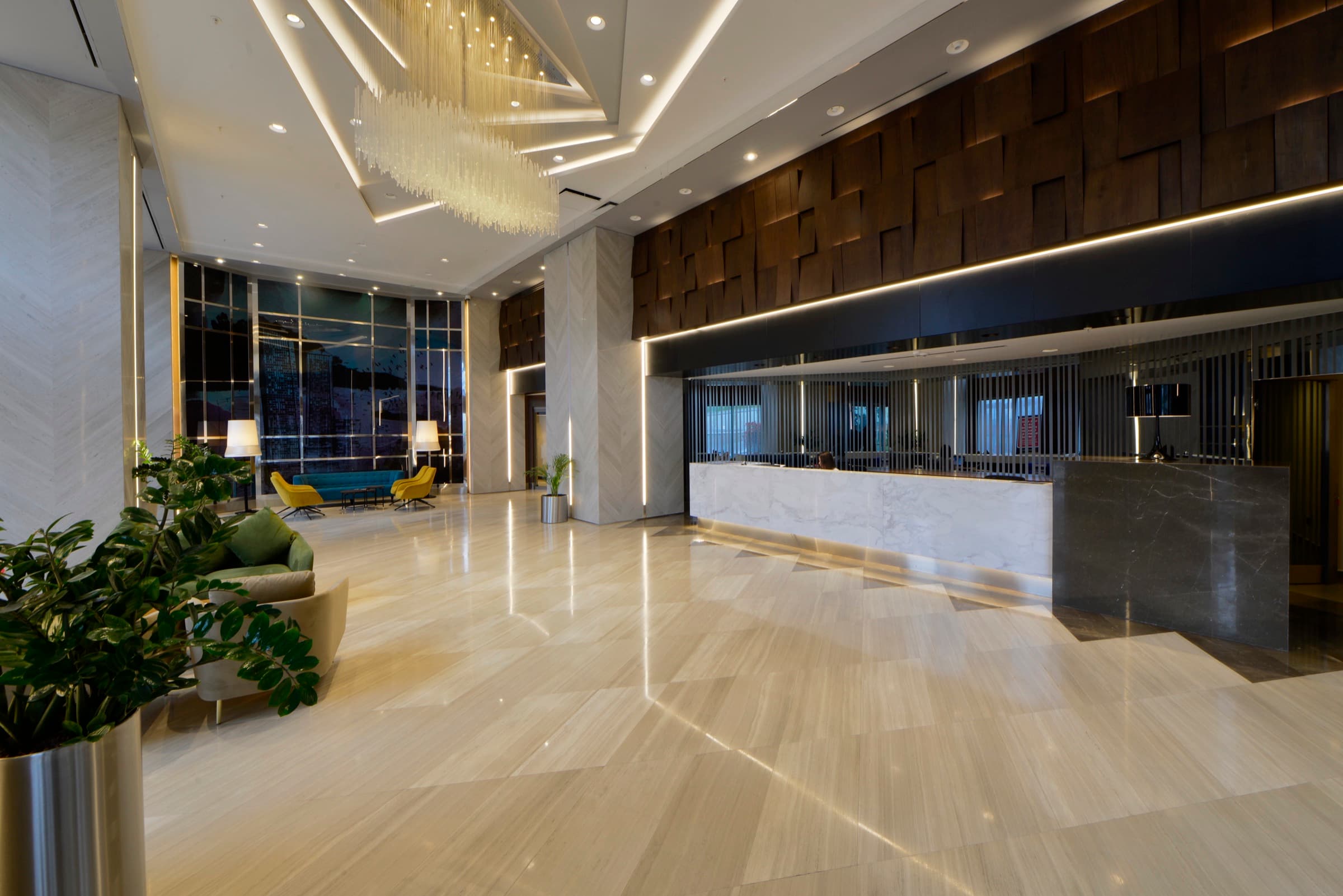Skyland İstanbul'da Sky Residence kulesinin kristal avizeli ve ceviz rölyef duvarlı resepsiyon lobisi
