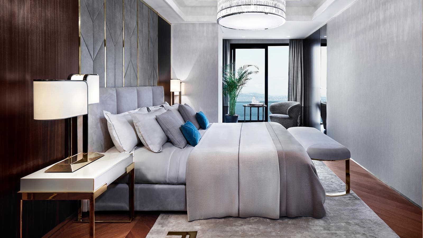 Bedroom with a grey upholstered headboard and dark wood paneling, balcony door opening to the sea view